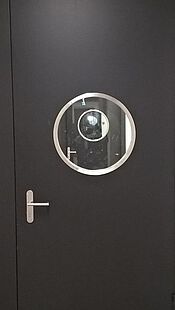 Security door in a security wing with a stainless steel ring as a glass frame